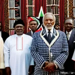 조모 케냐타 생애 - A dignified portrait of Jomo Kenyatta in traditional Kikuyu attire, standing confidently in front of...
